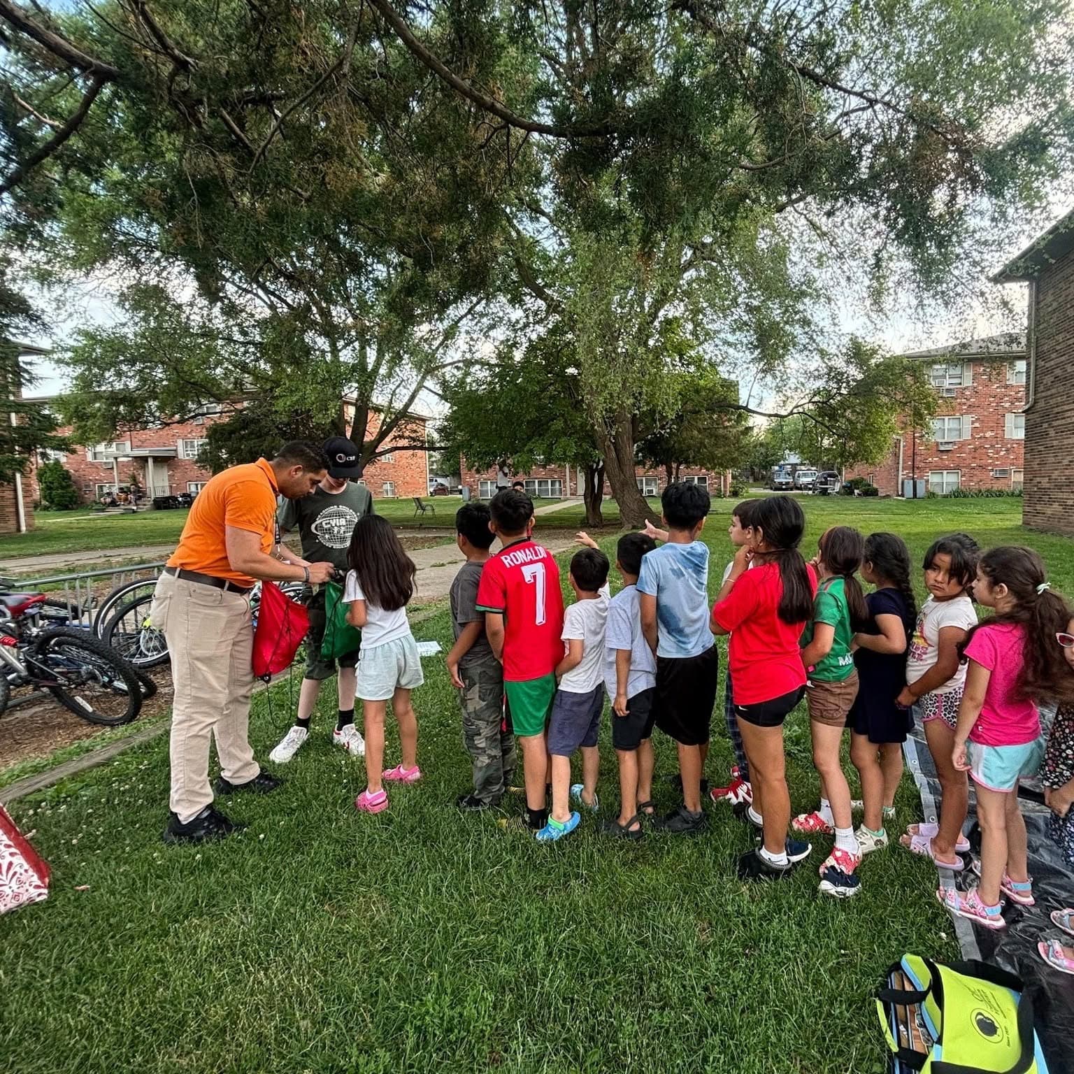 A leader stands with a line of children in a park