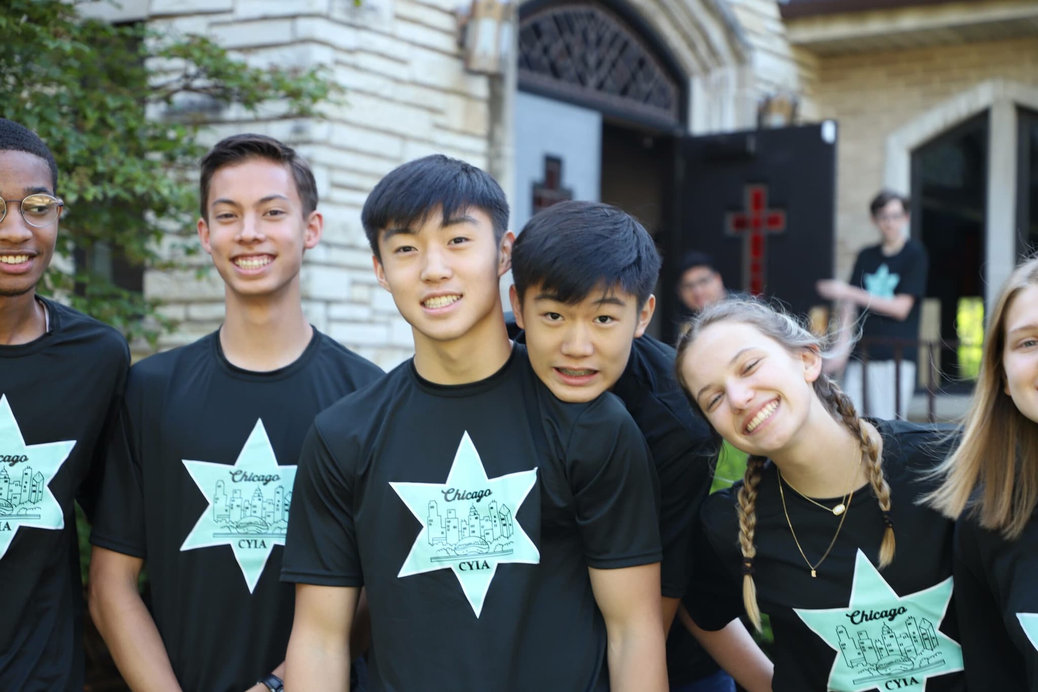 CYIA teens in matching Chicago CYIA shirts, arms around each other outside a church