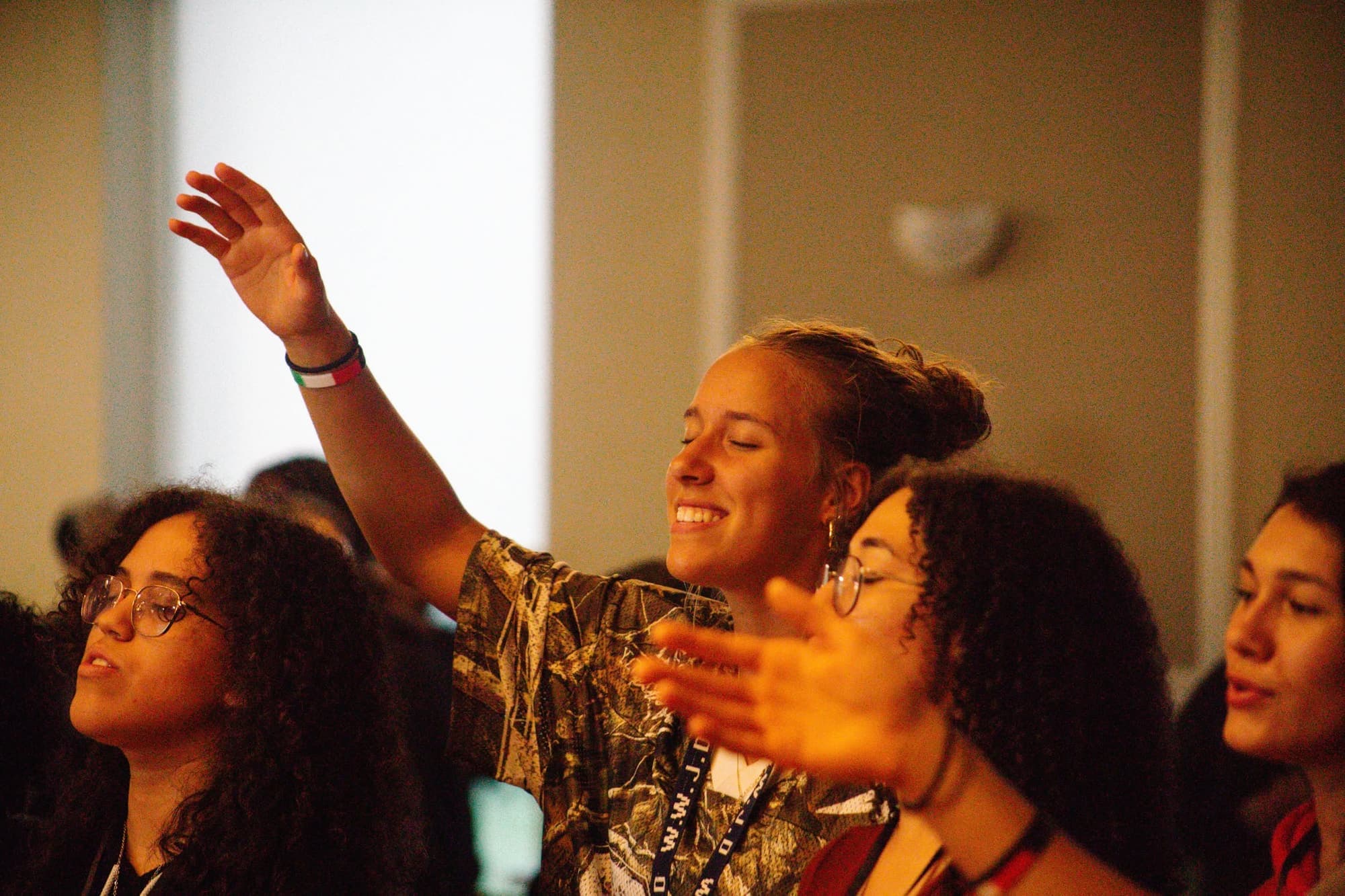 Teenagers sing together in warm light, one with a hand raised